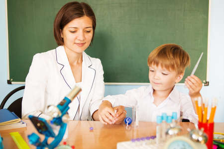 Teacher helping young boy with writing lesson. Back to school concept.の写真素材