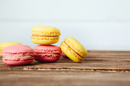 Sweet colorful French macaroon cookies dessert on brown wooden table over white wooden backgroundの写真素材
