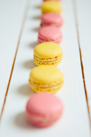 Sweet colorful French macaroon cookies dessert on white wooden tableの写真素材