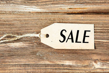 Blank label with word SALE on wooden background One paper blank tags with word SALE with rope on wooden background.の写真素材