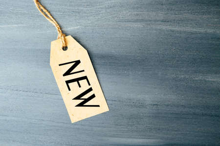Paper tag with word NEW on wooden background One paper blank tags with word NEW with rope on wooden background.の写真素材