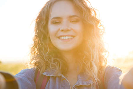A world without borders. Image of young pretty woman making selfie in the mountain forest. Looking at camera and smile.Young woman selfie on the beautiful nature view in mountains.の写真素材