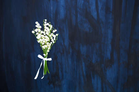 Wonderful fragrant white flowers with a delicate scent. Lily of the valley flowers on black wooden tableの写真素材