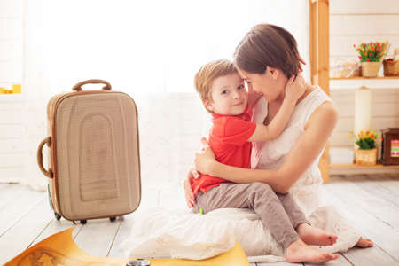 Go to new adventures and discoveries. Mom and baby girl with suitcase baggage and clothes ready for traveling on vacationの写真素材