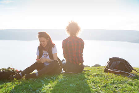 Pretty traveling women on top of mountain at sunset and using mobile phone.の写真素材