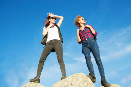 Two young beautiful girls tourists on top of the mountain.の写真素材