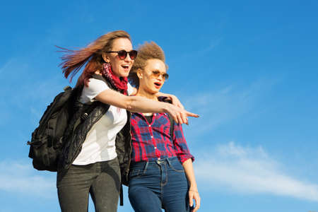 Two happy girls tourist at top of mountain at sunset outdoors during a hike in summerの写真素材