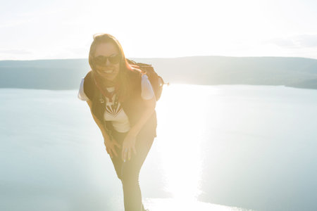 Beautiful girl Trist on top of a mountain on a background of sunset and sea. Woman hiker on a top of...