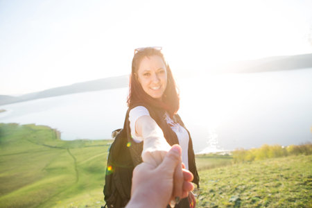 Follow me, Attractive brunette girl holding hands with leads in mountain valleyの写真素材