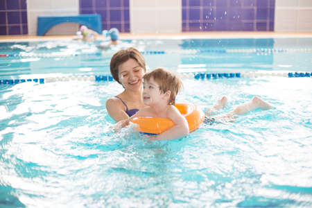 Mother and baby swim in the pool. Healthy family mother teaching baby swimming poolの写真素材