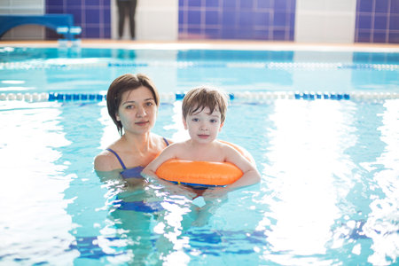 Mother and baby swim in the pool. Healthy family mother teaching baby swimming pool