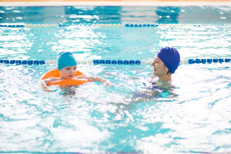 Baby with mom learns to swim in the pool. Mom teaches her son to swimの写真素材