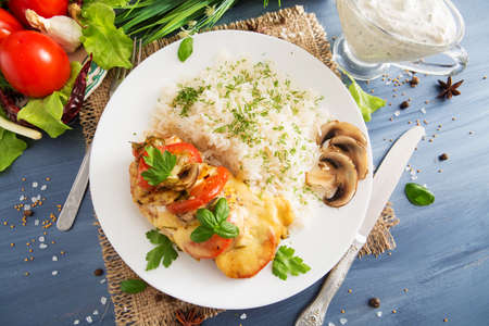 Chicken fillet baked in cheese with rice and vegetables. Fired cordon blue chicken served with rice and parsley on plateの写真素材