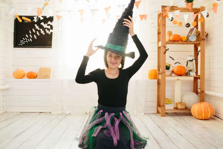 Young beautiful woman in witch costume ready for Halloween celebration in Halloween room decorationの写真素材