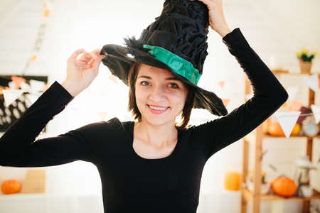 Young beautiful woman in witch costume ready for Halloween celebration in Halloween room decorationの写真素材