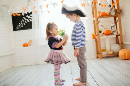 Boy in a pirate costume and a girl in a witch costume celebrates Halloween at homeの写真素材