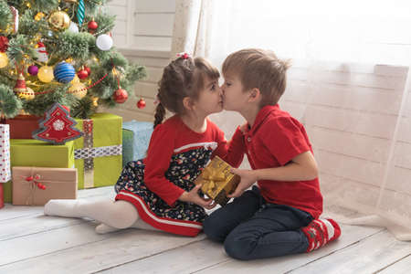 Boy gives a Christmas present to a girl in a bright sunny roomの写真素材