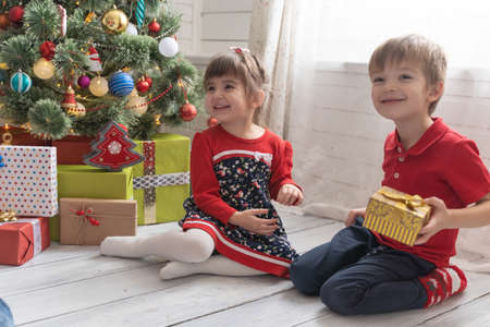Boy gives a Christmas present to a girl in a bright sunny roomの写真素材