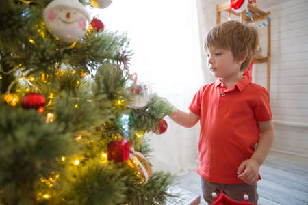 Little boy decorating the Christmas tree at homeの写真素材