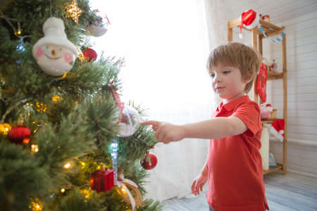 Little boy decorating the Christmas tree at homeの写真素材