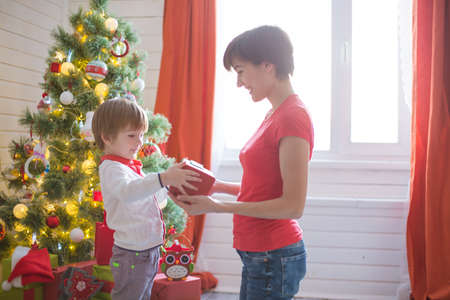 Happy family and Merry Christmas. Mother and baby son at Christmas morning at treeの写真素材