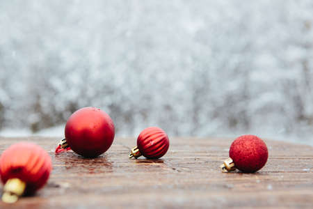 Beautiful Christmas bauble decorations lie on the wooden table over snow covered forest background.の写真素材