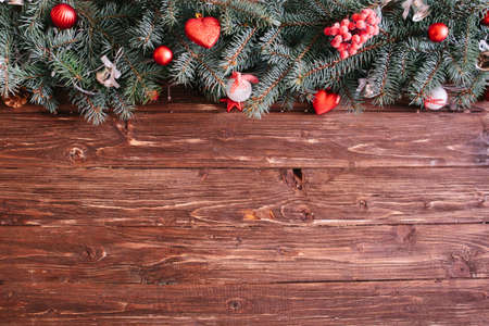 Blurred Christmas background, with fir branches, fairy lights and christmas decorations on wooden plankの写真素材