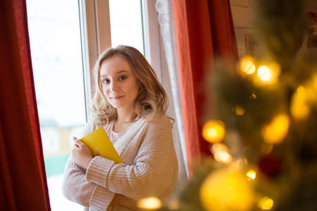 Beautiful, young woman decorating a Christmas tree at homeの写真素材