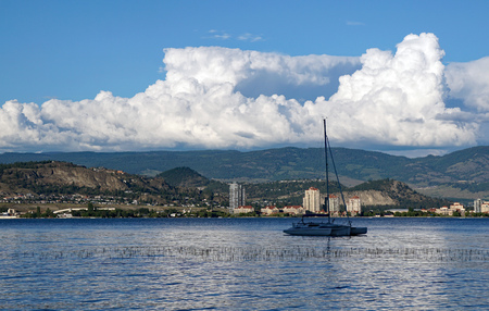 Trimaran boat on Okanagan Lake with the City of Kelowna in the backgroundの写真素材