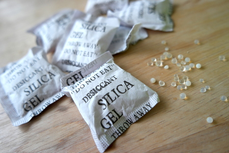 Silica gel packets on a wooden surface. Silica gels scattered on a wooden surface.の写真素材