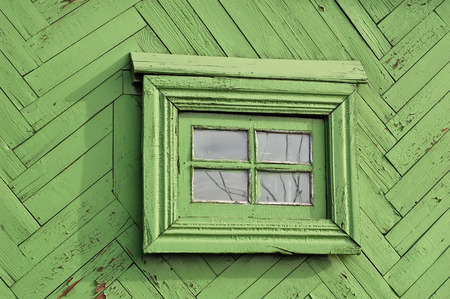 Old rustic oil painted wooden bars wall with small window reflecting tree branchesの写真素材