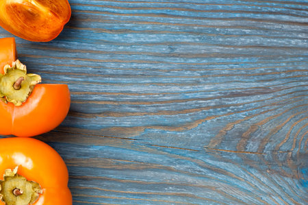 Ripe juicy persimmons on blue cracked rustic wooden board with place for textの写真素材