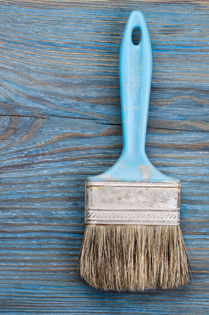 Used paint brush on blue rustic wooden board with place for textの写真素材