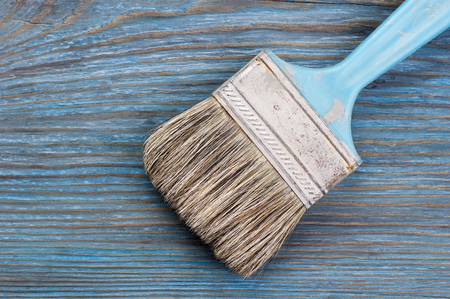 Used paint brush on blue rustic wooden board with place for textの写真素材