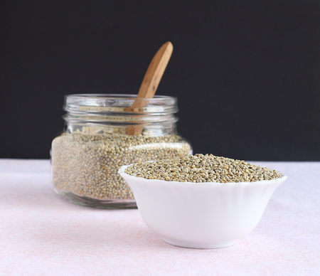 Healthy food pearl millet in a bowl and in the background is a jar with the same millet and a wooden spoon.の写真素材