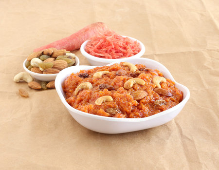 Carrot halwa or pudding, a traditional, popular and delicious Indian sweet dish, along with carrot gratings and almonds, raisins and cashew nuts.の写真素材