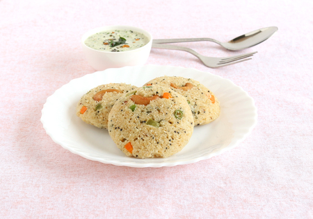 Oats Idli or cake, a healthy Indian vegetarian steam-cooked food, which also has vegetables like carrot, peas, green beans and capsicum, and cashew nuts, and coconut chutney.の写真素材