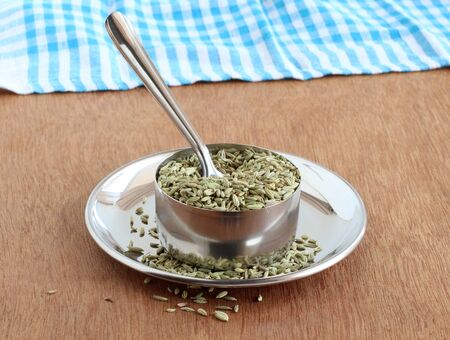 Fennel seeds, or soumph, a healthy food, are said to aid digestion and work as a mouth freshener, in a steel bowl with a spoon on a steel plate.の写真素材