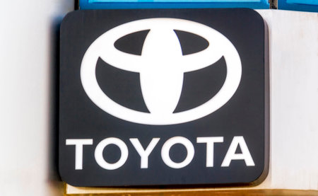 Toyota logo near a car dealer building. Toyota Motor Corporation is a Japanese multinational...