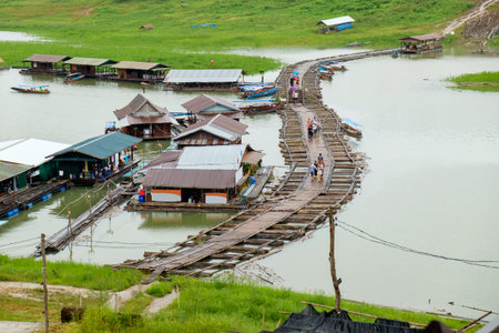Tourist walking on village antique and wooden bridge traditional culture in dam at sangkhlaburi,kanchanaburi,thailandの写真素材
