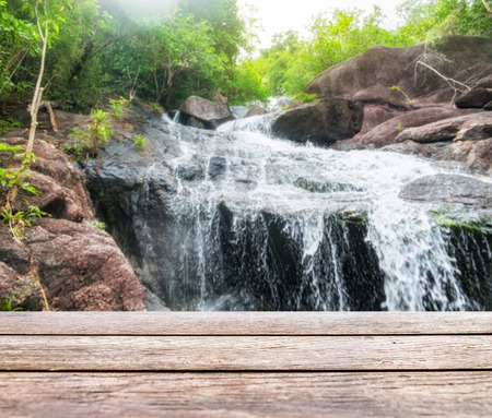 Wood table top on blurred waterfall flowing bright natural shining backgroundの写真素材