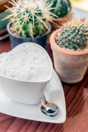 Hot coffee cup shape heart on wooden table plant cactusの写真素材