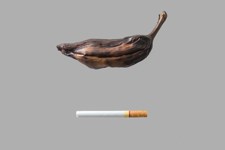 Cigarette cause of wither banana,on gray backgroundの写真素材
