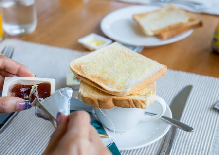 Hand woman holding bread with fruit jam on wood tableの写真素材