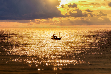 Fisherman with fishing boat sailing on golden sea in morningの写真素材