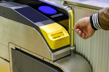Man hand inserting ticket subway card in entrance machine