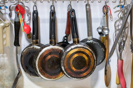 Kitchenware pan and spoon hanging on rack in kitchen