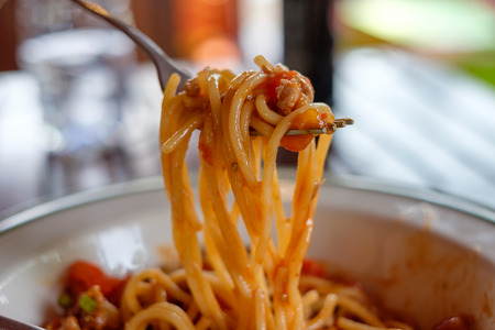 Close-up fork scooping spaghetti pork tomato sauceの写真素材