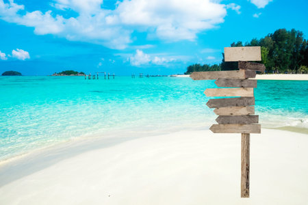 Wooden arrows signboard on beautiful tropical sea with white beach