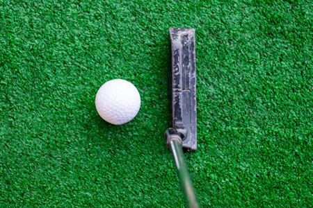 Golfer preparing on training putt with golf ball on mini golf